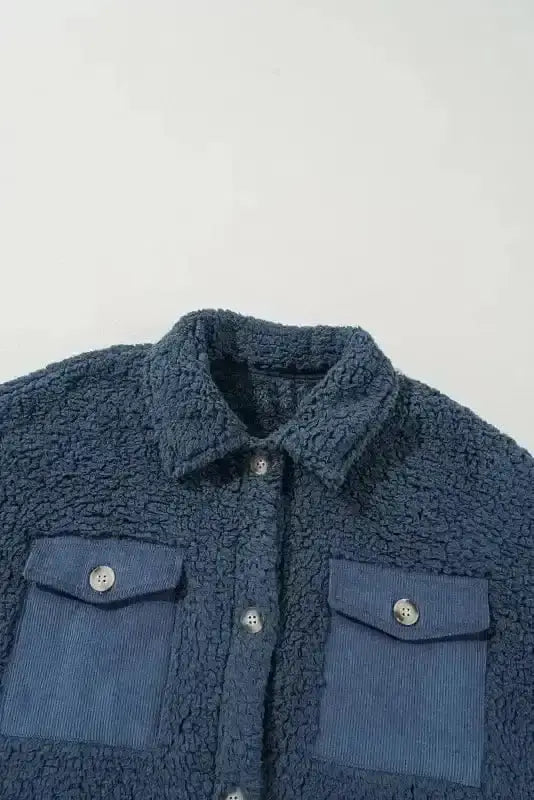Cozy blue teddy coat with soft fleece texture and chic corduroy chest pockets, perfect for winter outerwear style and warmth.