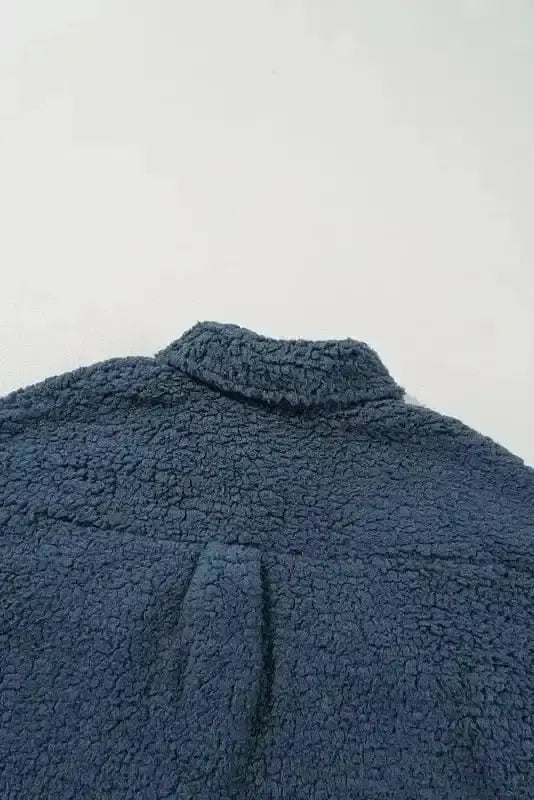 Close-up of the back collar and yoke seam on the blue teddy coat, emphasizing its cozy fleece fabric and structured tailoring.