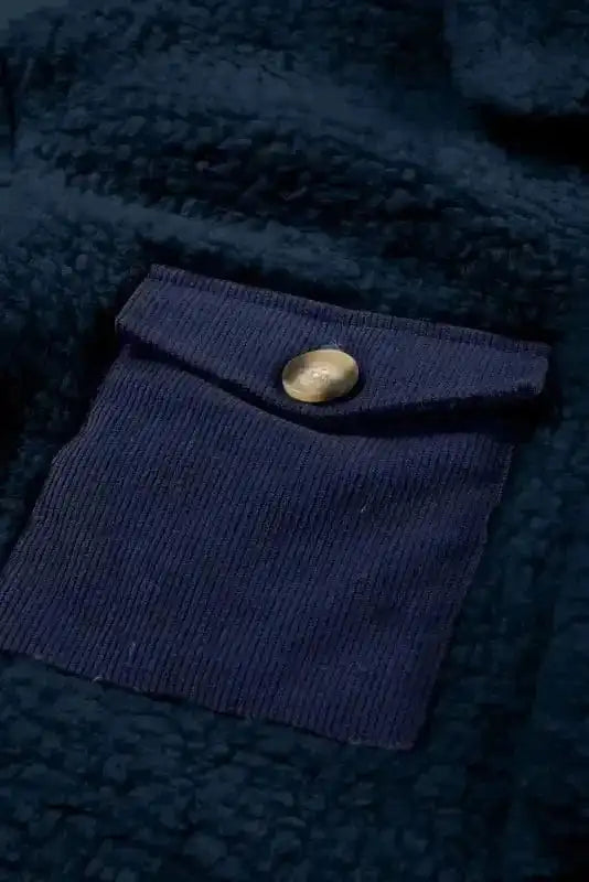 Detailed view of the navy contrast pocket with button on the blue teddy coat, adding a chic accent to the cozy design.