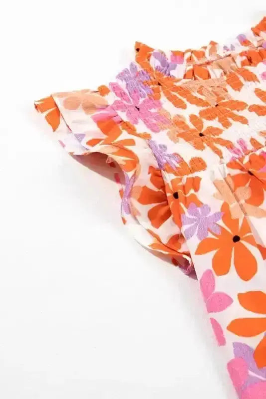 Close-up of ruffled sleeve and smocked neckline on Orange Smocked Floral Top. Bold floral print perfect for casual styling.