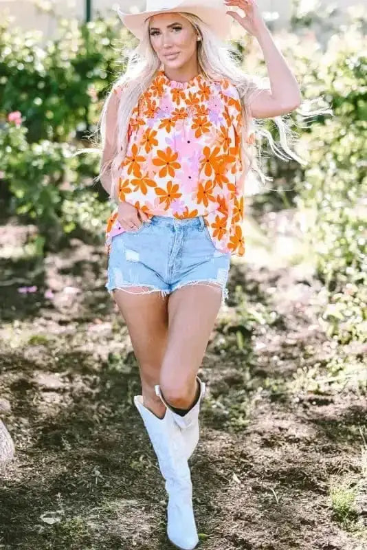 Full outfit view featuring Orange Smocked Floral Top with denim shorts and white boots. Trendy summer look from FashionFitz.
