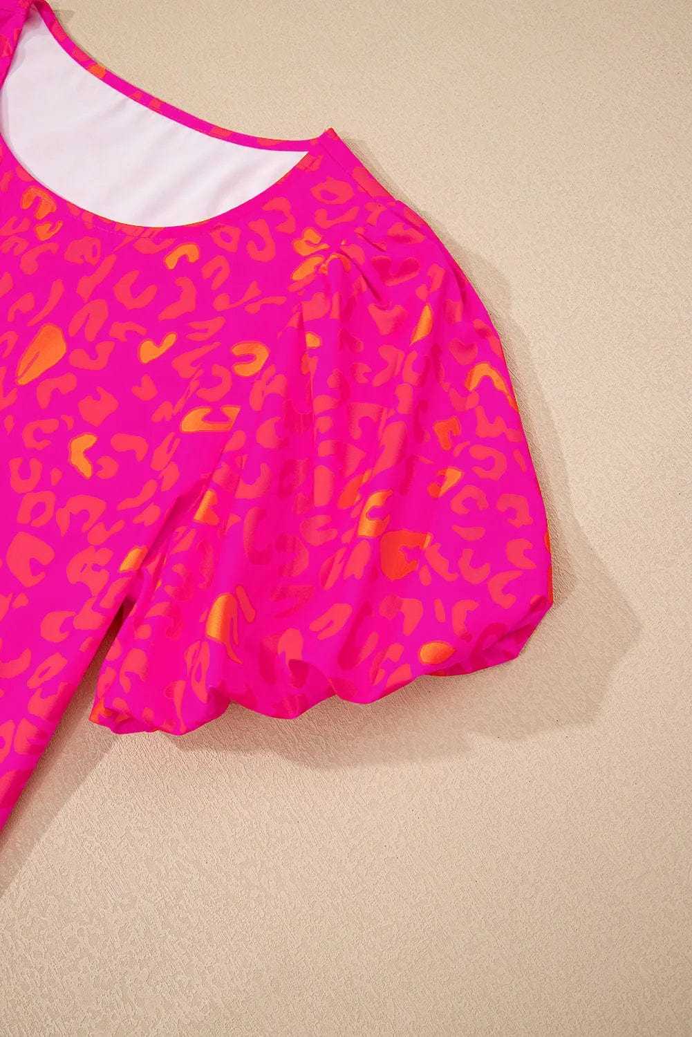 Detail shot of the leopard print pattern and puff sleeve stitching on the pink top.