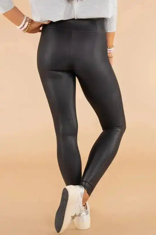 Back view of women’s high-rise black faux leather skinny leggings, showcasing smooth finish and flattering silhouette for fall fashion.
