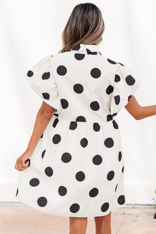 White polka dot mini dress showing half-button placket and ruffled sleeve detail, side view, Fashionfitz