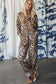 Woman wearing a leopard print lounge set with a colorful zipper against a patterned curtain background.