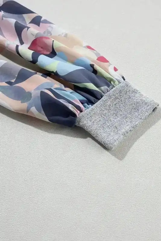 Detailed view of elastic cuff and sheer floral sleeve on Gray Floral-Sleeves Buttoned V-Neck Top.