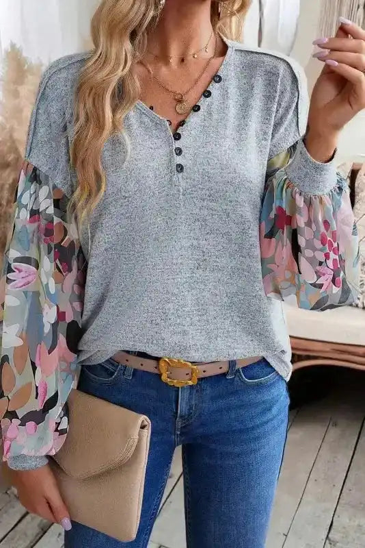 Front close-up of Gray Floral-Sleeves Buttoned V-Neck Top paired with jeans, emphasizing button detail and vibrant sleeve pattern.