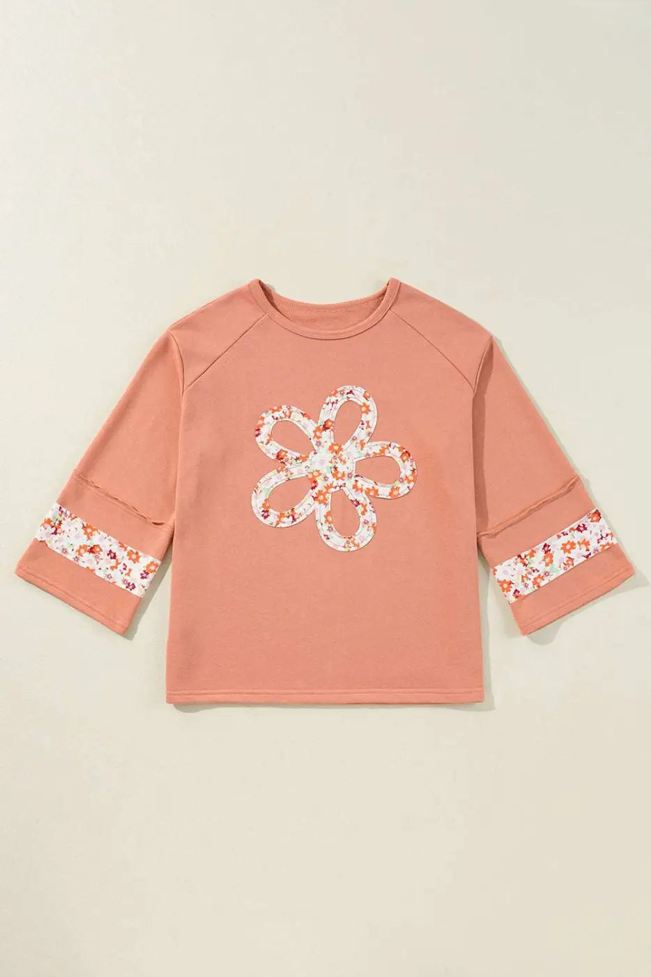 Flat lay of Flower Patch Graphic Top featuring floral patchwork on front and sleeves, showcasing its versatile fit and spring-ready design.