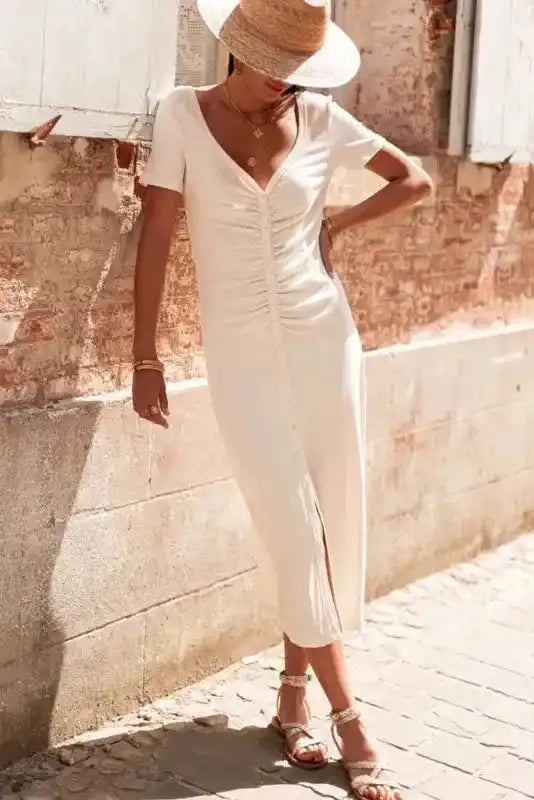 Model wearing Beige French T-shirt Dress with V-neck and front slit, styled with sandals and a straw hat for a chic summer look.