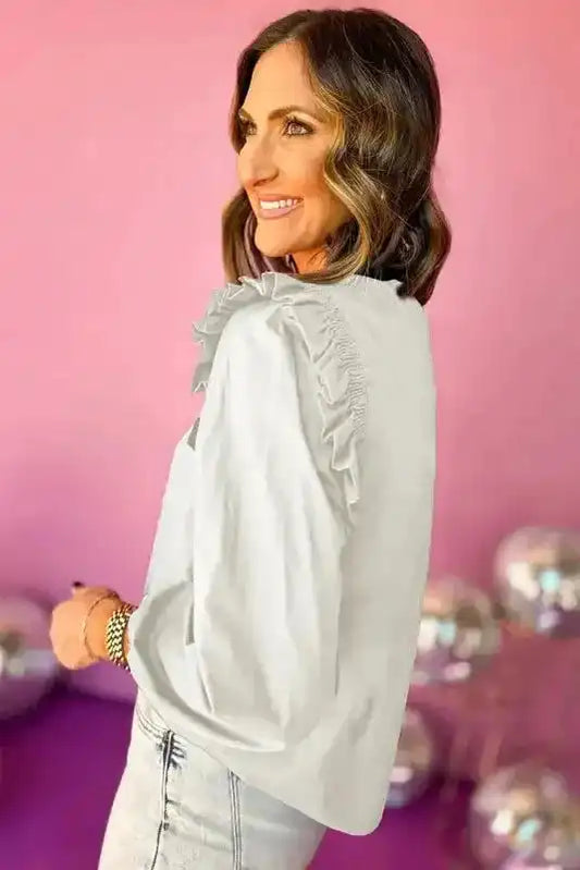 Side view of white frilled neck blouse featuring ruffled shoulder detail and puff sleeves. Elegant and chic for casual or office outfits.