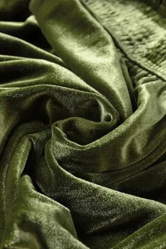 Swirled green velvet fabric detail from the dress, highlighting its rich texture and sheen for winter fashion appeal.