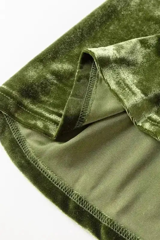 Close-up of green velvet fabric from the Frilled Neck Smocked Bodice Velvet Dress by FashionFitz, showcasing soft texture and stitching detail.