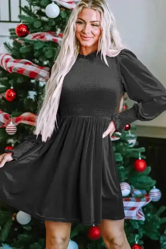 Model wearing the Frilled Neck Smocked Bodice Velvet Dress by FashionFitz in front of a Christmas tree, featuring a smocked bodice and puff sleeves.
