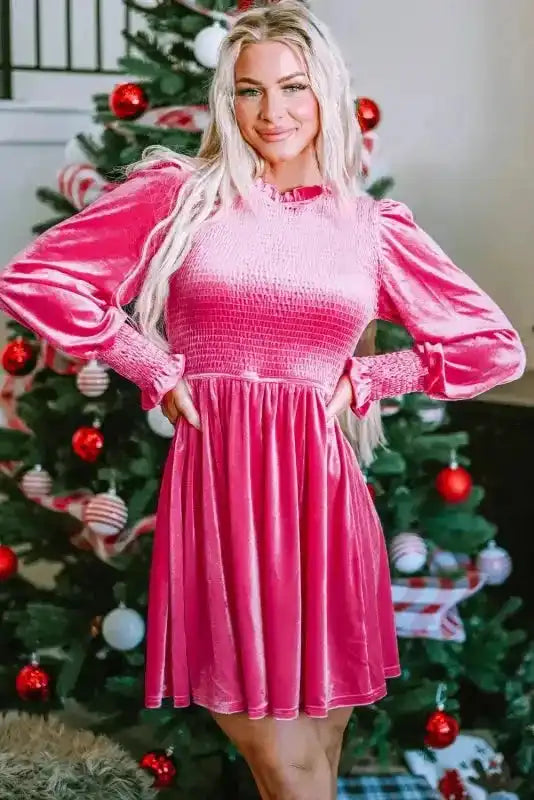Front pose of pink Frilled Neck Smocked Bodice Velvet Dress with holiday decor, ideal for festive fashion.