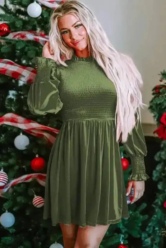 Front view of green Frilled Neck Smocked Bodice Velvet Dress styled for the holidays, featuring long sleeves and A-line silhouette.
