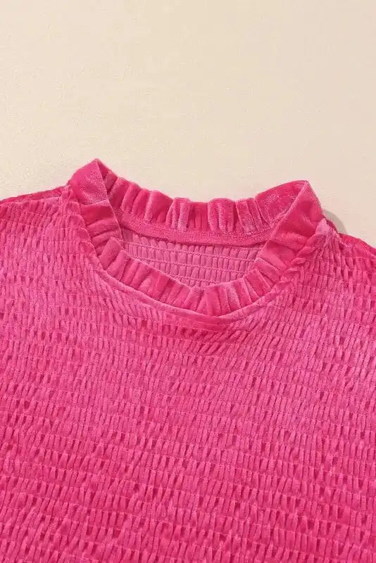 Close-up of frilled neckline and smocked bodice on pink velvet dress from FashionFitz. Elegant texture ideal for winter occasions.