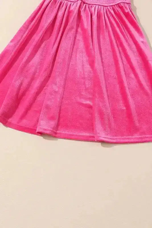 Detail of pink smocked sleeve with frilled cuff, highlighting craftsmanship and soft velvet fabric.