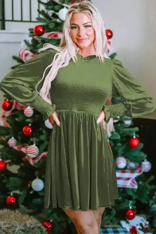 Model posing in green velvet mini dress with smocked bodice and frilled neckline, perfect for Southern Belle-inspired winter fashion.