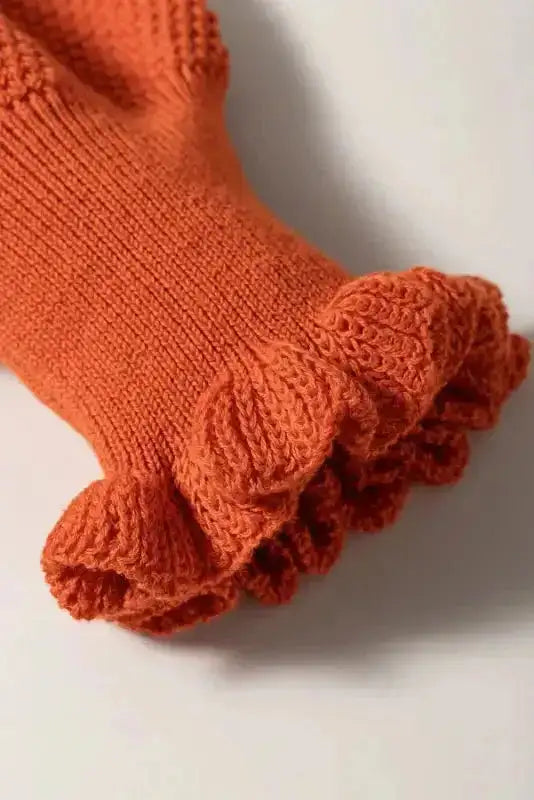 Close-up of ruffled cuff on puff sleeve of rust knit top, showcasing intricate summer knit detailing.