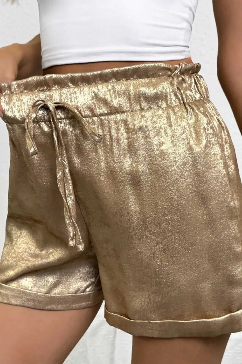 Close-up of Gold Metallic Shorts Women highlighting luxe shimmer fabric, drawstring waist, and modern cuffed hem for a trendy summer look.
