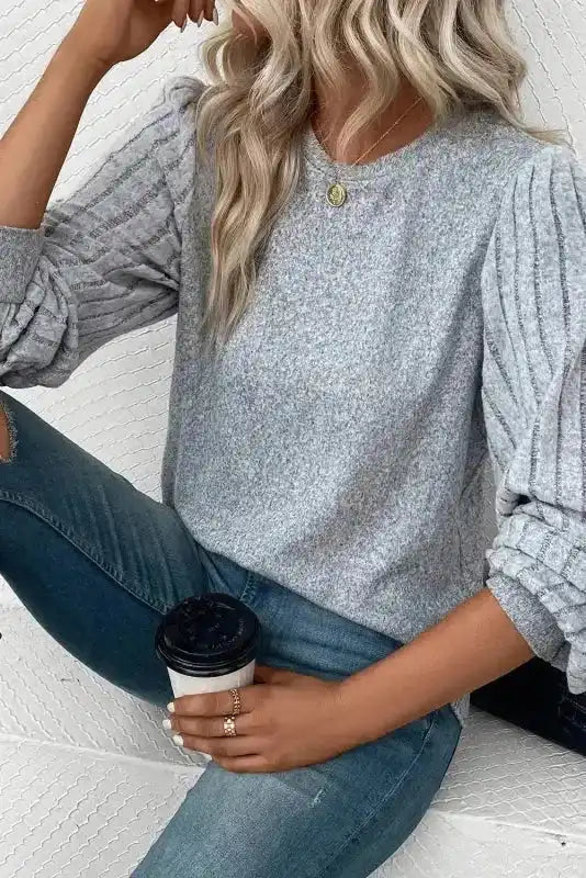 Model seated in grey Ribbed Bishop Sleeve Top, showing cozy knit fabric and voluminous sleeves perfect for autumn.