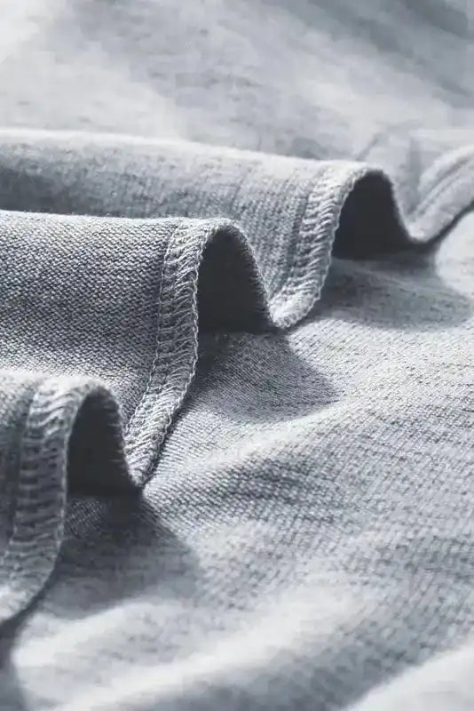 Macro shot of grey knit fabric from Ribbed Bishop Sleeve Top, showcasing soft and stretchy material.