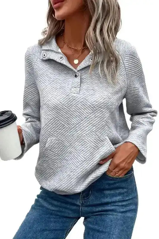 Gray ribbed pullover top with buttoned neckline and casual fit, styled with jeans for a cozy winter look.