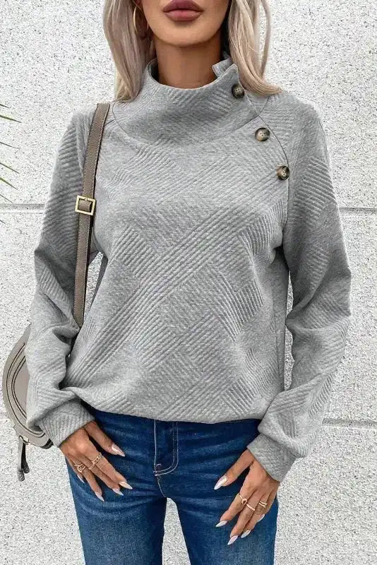 Gray ribbed textured top with high buttoned collar and relaxed silhouette, ideal for casual winter outfits.