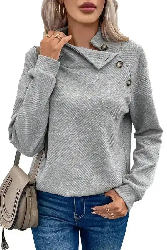 Gray ribbed pullover top with buttoned collar and relaxed fit, styled with crossbody bag for a casual winter outfit.