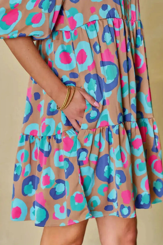 Close-up of multi-colour tiered dress fabric and pocket detail, showcasing bold print and practical design in trendy mini dress style.