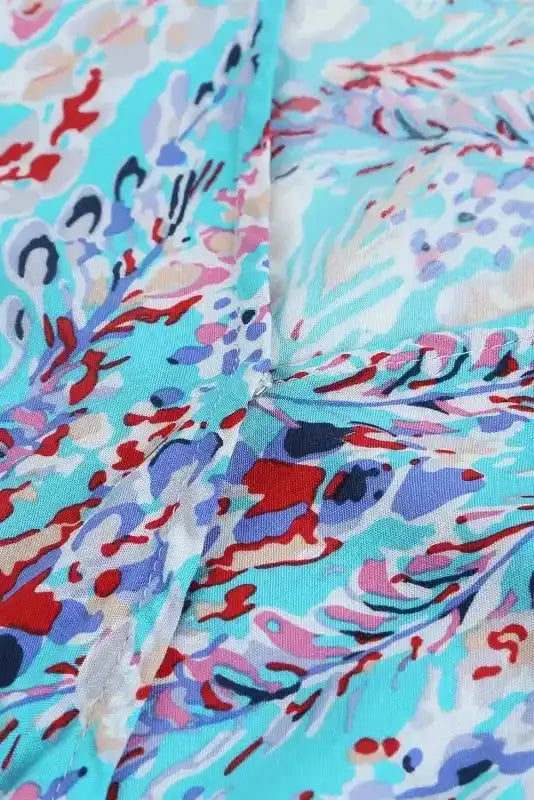 Detailed view of floral abstract print on green wrap maxi dress, highlighting the vibrant summer colors and soft fabric texture.