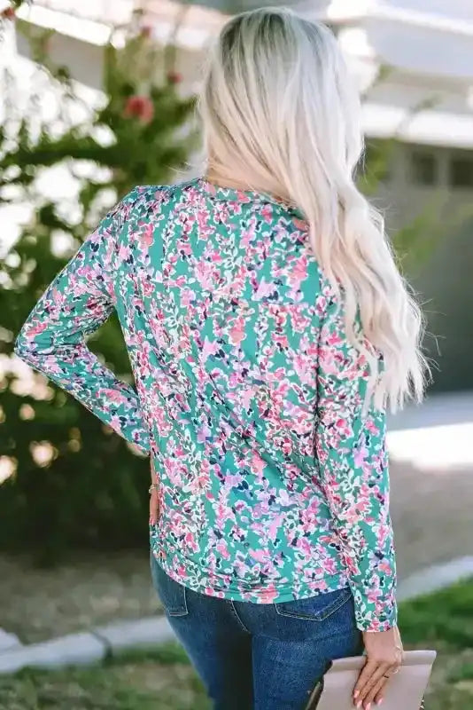 Back view of green floral long sleeve top showcasing abstract pink and purple print, paired with jeans for everyday wear.