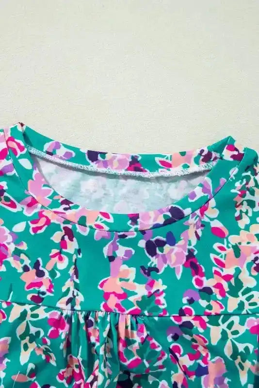 Close-up of neckline on green floral top with pink and purple abstract print, highlighting stitching and fabric detail.