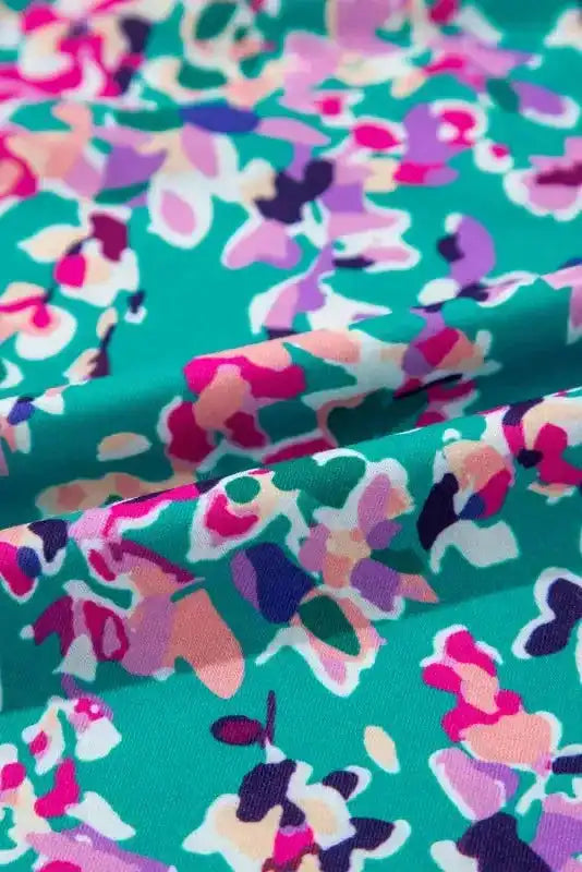 Macro view of green floral fabric with pink, purple, and peach abstract print, showing soft material texture.
