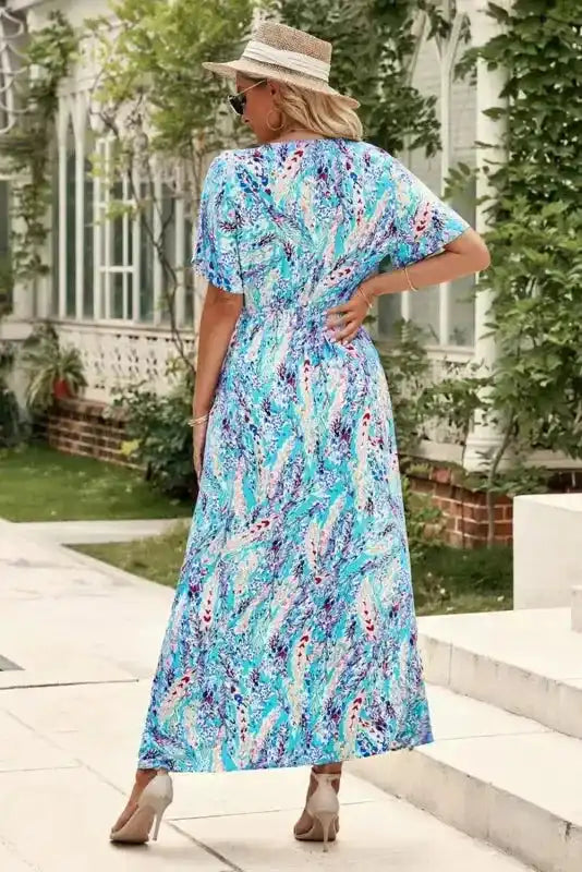 Back view of wrap-style floral maxi dress in green with abstract print, highlighting the flowy design and summer-ready fabric.