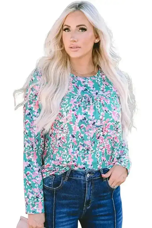 Studio shot of green floral long sleeve top with pleated front detail, styled with dark denim jeans.
