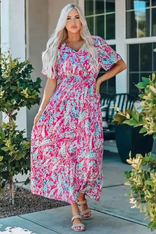 Pink version of floral maxi dress with v-neck and wrap top, styled outdoors for a breezy summer look.