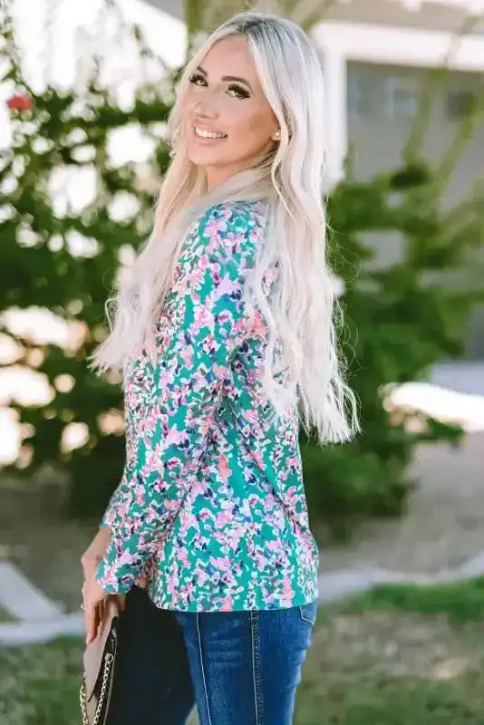 Side view of green floral print long sleeve top with soft pleats, styled with dark denim for a relaxed outfit.