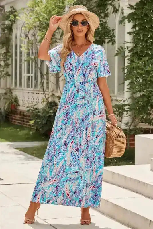 Floral wrap maxi dress in green with V-neck and flutter sleeves, styled with summer accessories for a breezy, elegant look.