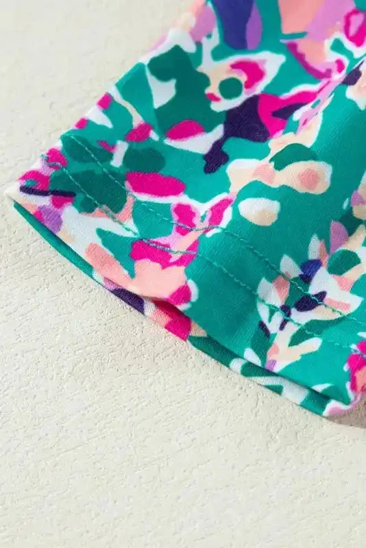 Hem detail of green floral top with pink and purple print, showing stitching and fabric quality.