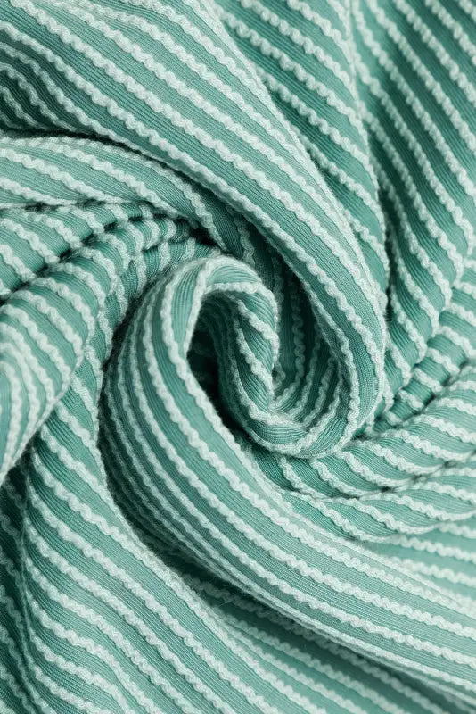 Swirled green and white striped fabric texture on a grey corded wide leg jumpsuit – relax relax