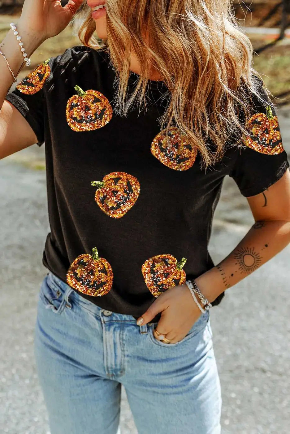 Person wearing a Sequin Pumpkin Face Halloween T-Shirt  - Halloween-themed pumpkin designs and blue jeans.