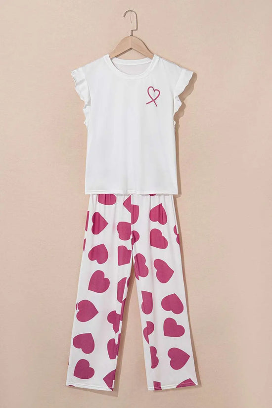 White top with a pink heart design and heart-patterned pants on a beige background
