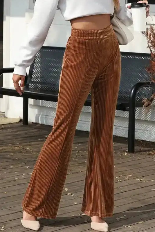 Outdoor view of women's high waist flare corduroy pants in rich brown, styled casually with a cropped sweatshirt and flats.