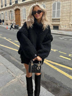 Black fluffy chunky knit turtleneck jumper styled with a designer handbag and knee-high boots, perfect for chic winter streetwear.