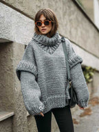 Gray fluffy chunky knit turtleneck jumper styled with black jeans and orange sunglasses, a cozy and chic winter look.