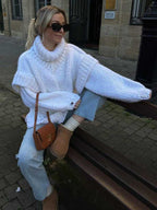 White fluffy chunky knit turtleneck jumper paired with jeans and UGG boots, a relaxed and warm winter outfit.