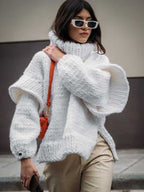 White fluffy chunky knit turtleneck jumper worn with beige trousers and orange accessories, a chic oversized winter sweater look.