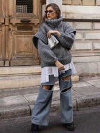 Gray fluffy chunky knit turtleneck jumper layered over a white shirt with ripped jeans, a trendy streetwear winter look.