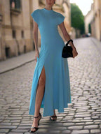 Woman in a blue maxi dress with a high slit standing outdoors with scenic background